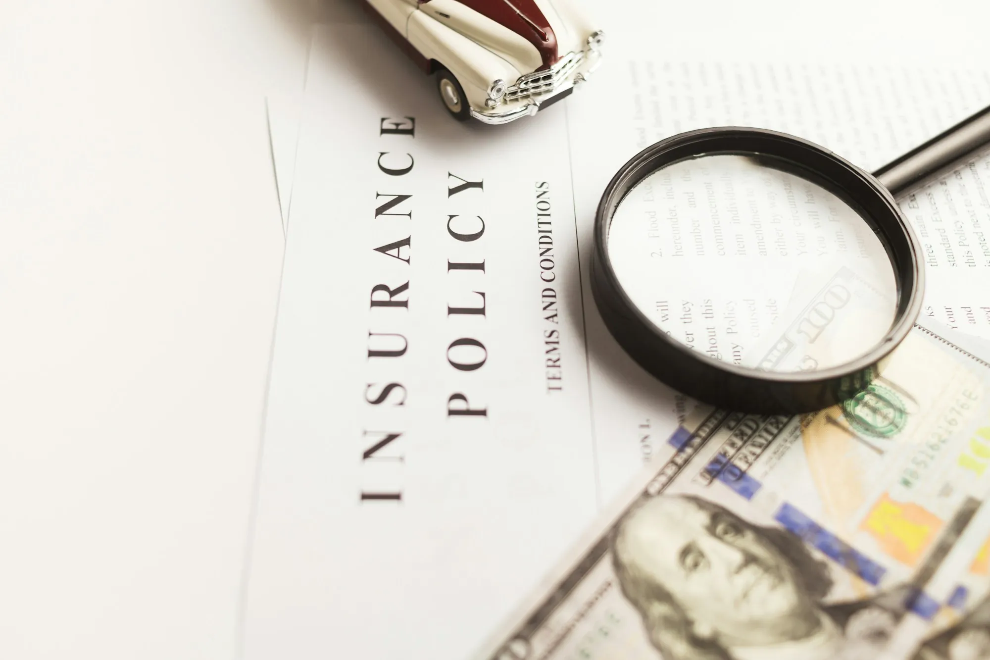 Insurance policy paper with a magnifying glass and cash