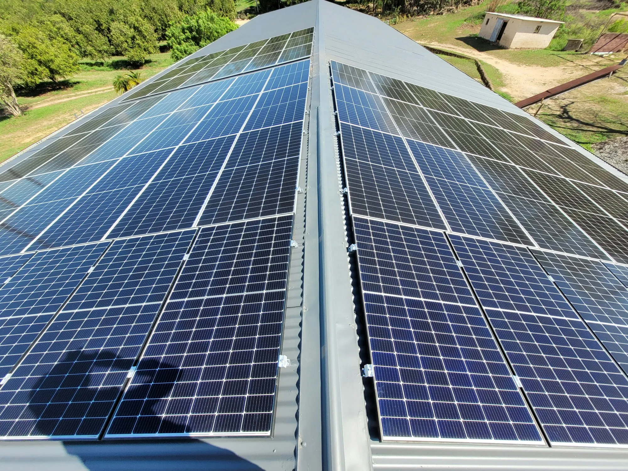 Rows of blue solar panels meeting at a roof ridge